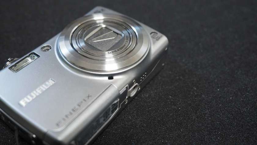 FujiFilm FinePix F100fd の写真。カメラ本体が斜めに映し出されている。レンズ部分に注目して映し出されている。